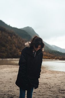 a woman standing on a beach next to a body of water